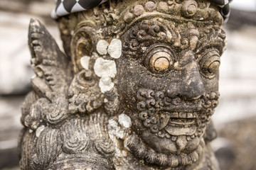 Wall Mural - Traditional guard demon statue carved in dark stone on Bali island, Indonesia