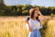 © Alena Popova - Girl in hat shooting photo walking in golden dried grass field with camera