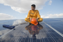 Closeup Of Engineers  Or Worker Hold In Hand Orange Helmet Wearing Orange Bear Coat. Sitting On A Solar Cell.