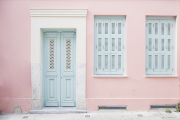 Pastel pink building and pale blue doorway surrounded by marble in Athens, Greece