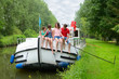 Family vacation, travel on barge boat in canal, happy kids having fun on river cruise trip in houseboat
