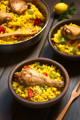 Wall Mural - Chicken paella, a traditional Valencian (Spanish) rice dish made of rice, chicken, peas and capsicum , photographed on dark wood with natural light (Selective Focus on the chicken thigh)