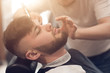 © britanskiy - a master in the barbershop works with the client. shaves beard young guy. shaving with a straight razor