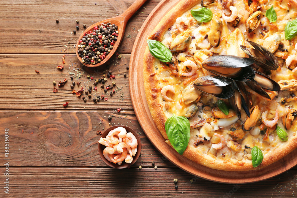Delicious pizza with seafood on wooden background