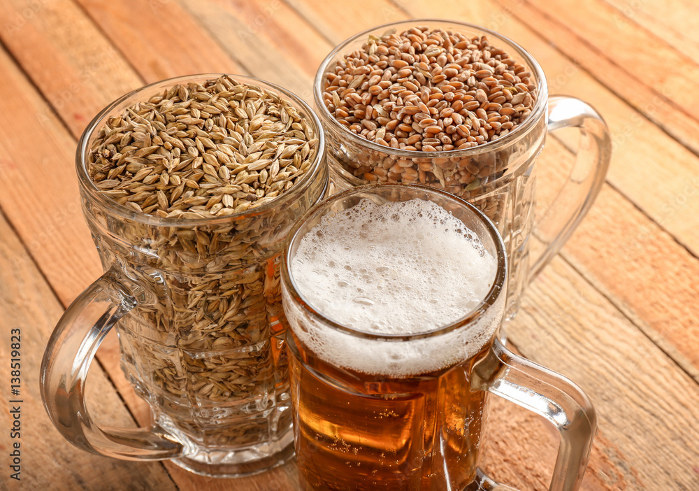 Glasses with fresh beer, wheat and barley on wooden background
