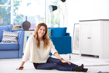 Wall Mural - Portrait of young woman sitting on floor in room