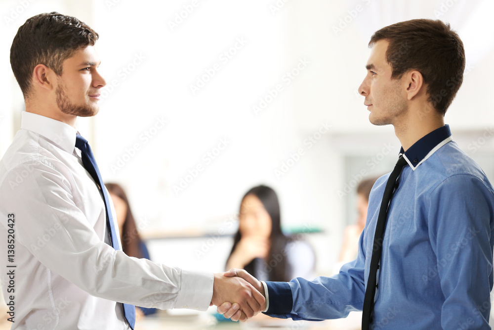 Handshaking of business partners on blurred people background