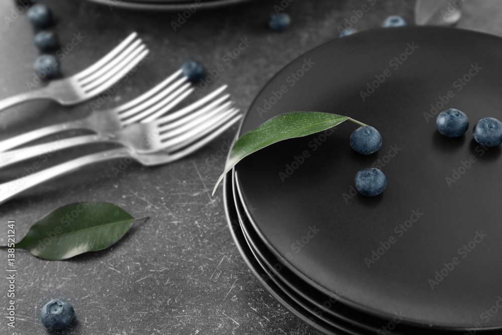 Black plates and cutlery on gray background