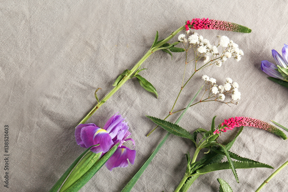Beautiful fresh flowers on grey textile background