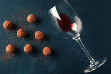 Wall Mural - Delicious chocolate truffles and wine glass on dark background