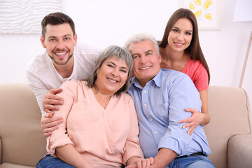 Wall Mural - Young couple with middle aged parents on sofa in the room