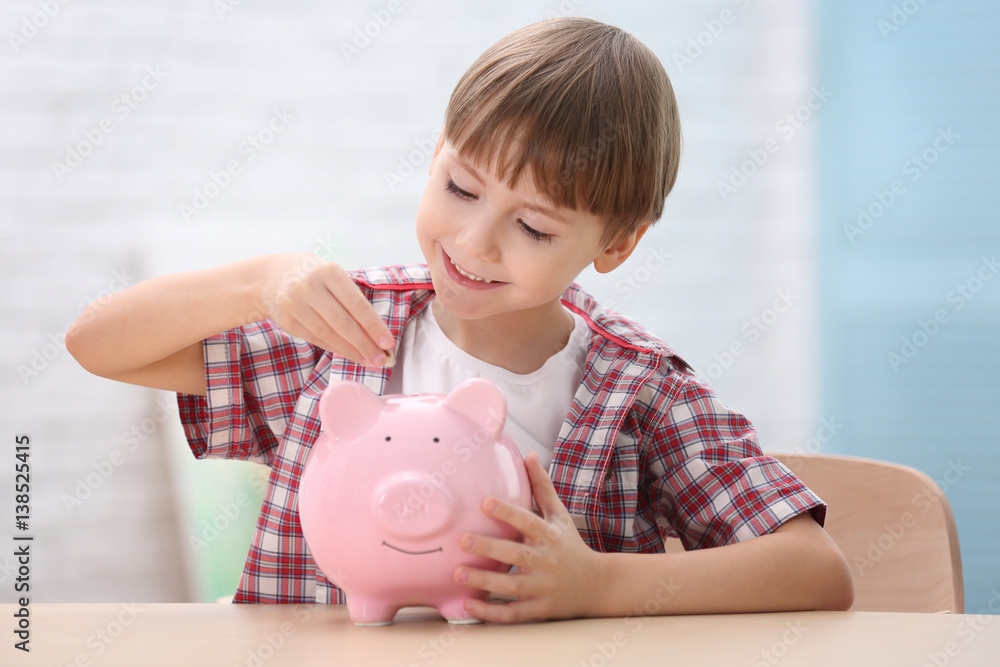Cute little boy with piggy bank on blurred background