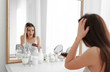 © Africa Studio - Young woman with hair loss problem in front of mirror at home