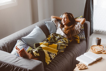 Canvas Print - Girl in blanket relaxing on couch in living room