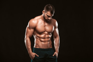 strong athletic man - fitness model showing his perfect back isolated on black background with copys