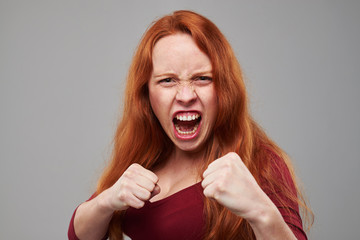 Anxious woman with red hair holding two fists