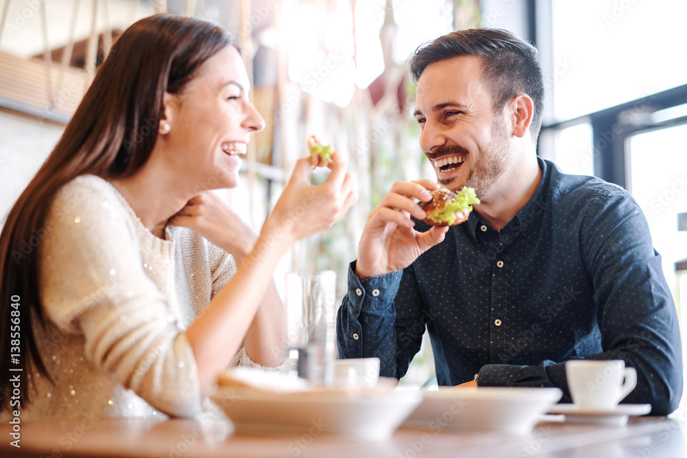 Beautiful young couple sitting in a cafe, having breakfast. Love, food, lifestyle