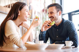 Fototapeta  - Beautiful young couple sitting in a cafe, having breakfast. Love, food, lifestyle