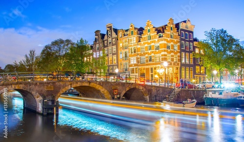 smugi-swiatel-statku-plywajacego-po-kanale-w-amsterdamie-w-godzinach-wieczornych