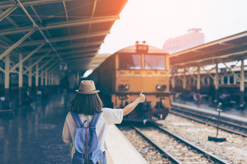 Wall Mural - Young woman traveler showing thumbs up in bangkok train station