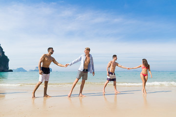 Wall Mural - two couple on beach summer vacation, young people in love walking, man woman holding hands sea ocean