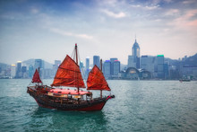 Traditional Wooden Sailboat Sailing In Hong Kong Harbour At Hong Kong City On Background 