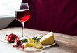 Glass of red wine, pomegranates and cheese on the table. Dark background. agriculture and farming. Banner for restaurant