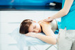 © Iryna - Close up of young woman having shoulders massage in spa. Therapist doing massage against blue background.