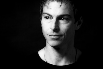 Close up portrait of handsome smiling caucasian man. Black background. Monochrome picture