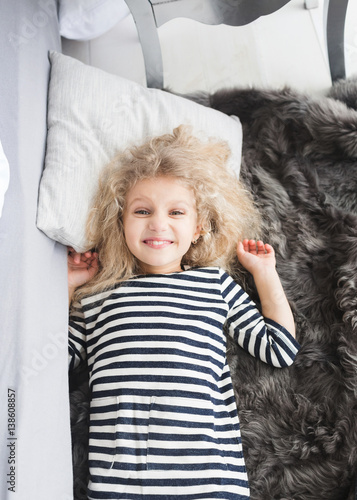 Little Girl With White Curly Hair In A Striped Vestin Bed Little