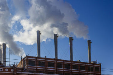 White smoke goes from a pipe on a background of blue cloudless sky