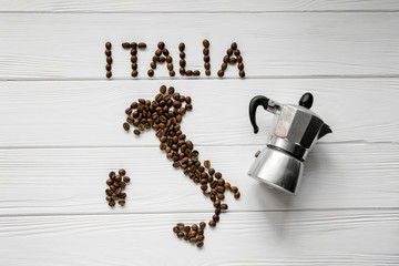 Wall Mural - Map of the Italy made of roasted coffee beans laying on white wooden textured background with coffee maker. Space for text