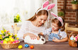 © JenkoAtaman - Happy easter! family mother and child daughter playing with a rabbit at home for the holiday