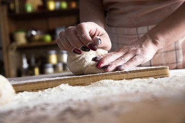 Wall Mural - Close up of female baker hands kneading dough and making bread