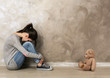 © Africa Studio - Little girl sitting with toy bear on color wall background
