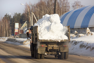 Full of snow loaded truck on russian city street. Spring snow cleaning