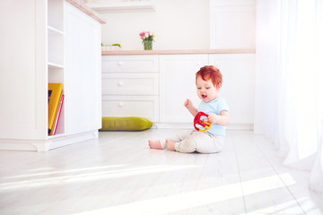 Wall Mural - cute ginger baby boy playing with toys in bright kitchen, at home