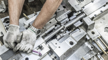 detail of worker's hands tightenning the screw in repaired big steel mechanical device