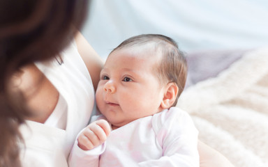 Mother with her newborn baby. Mother is holding her little baby girl.  Photo with the effect of sunlight, soft natural light, with selective focus.