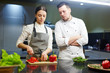 © pressmaster - Professional chef and his trainee cooking fresh vegetable salad