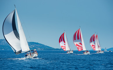 Sailing boat with black and white spinnaker catching up sailing boat on horizon