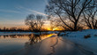 © gluuker - Scenic evening winter landscape. beautiful glow Dramatic sunset over the river to the coast suburb under snow and ice edge. February thaw