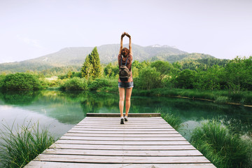 Wall Mural - Young woman with raised arms up on the nature background.