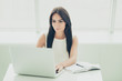 © deagreez - A portrait of beautiful businesswoman sitting at office and working with laptop