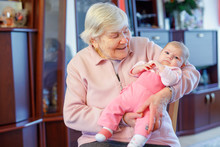 Great Grandmother Holding Newborn Baby Grandchild On Arm