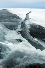 Ice hummocks on the northern shore of Olkhon Island on Lake Baikal. Fresh crack broke the thick ice. Fresh clean water rises from the depths and freeze in the cold. Ice Storm. Photo partially tinted