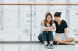 © interstid - Young happy Asian girls best friends laugh and smile while sitting and having fun with smart phone mobile indoor.