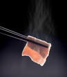 Sukiyaki or Shabu shabu pork slice in chopsticks with smoke isolated on black.