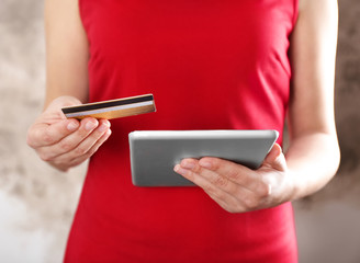 Woman holding credit card and using tablet, closeup