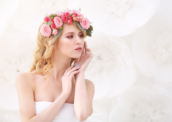 Wall Mural - Beautiful young woman with flowers in hair on light background